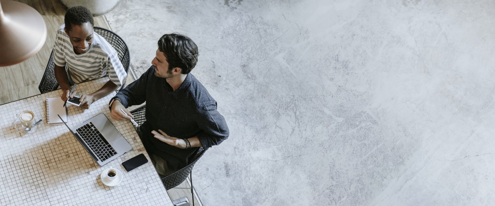 Business professionals talking over coffee and laptops at a cafe table